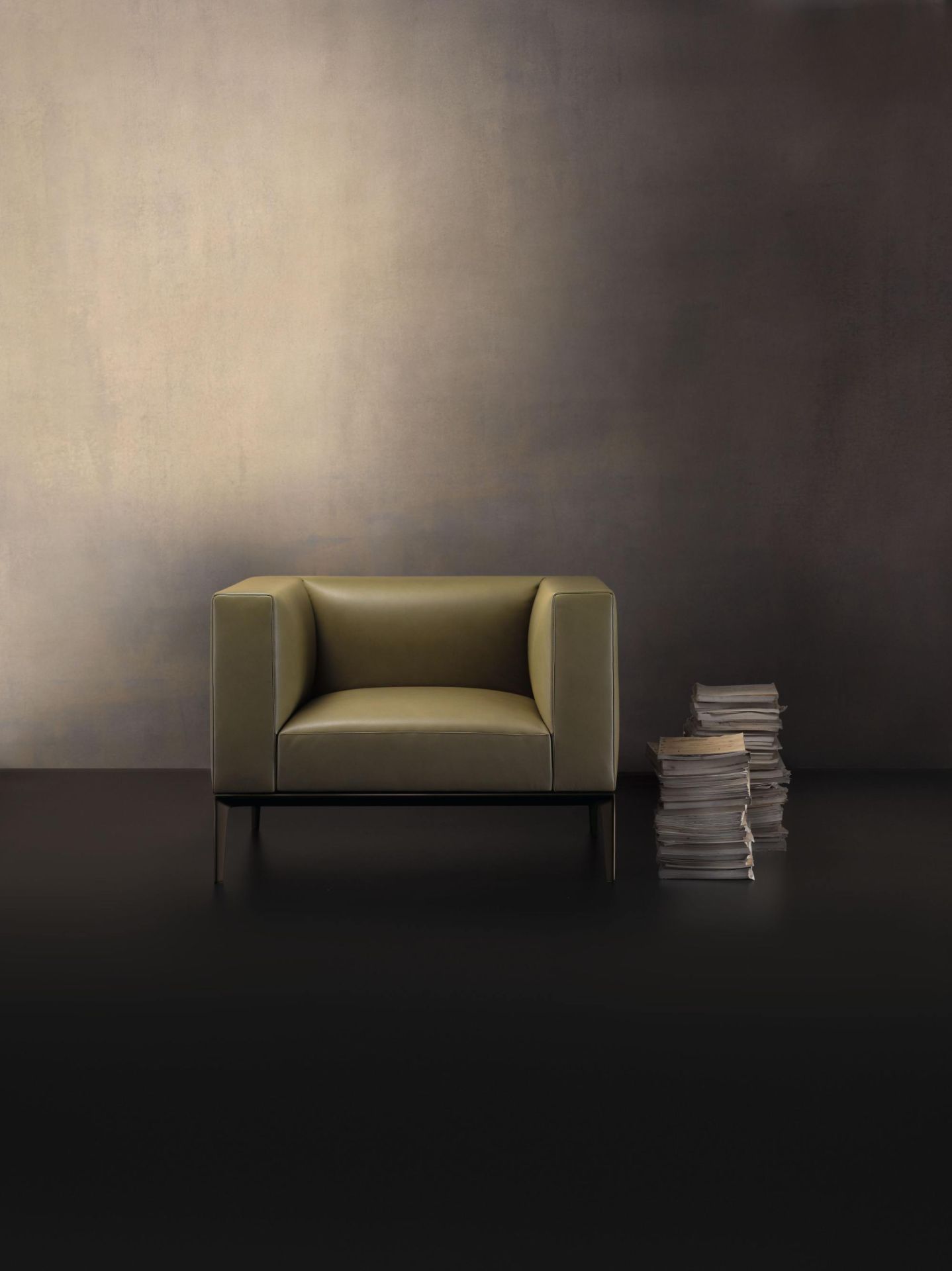 781 Jaan Sessel von Walter Knoll in olivgrünem Leder mit minimalistischem Design und Bücherstapel.