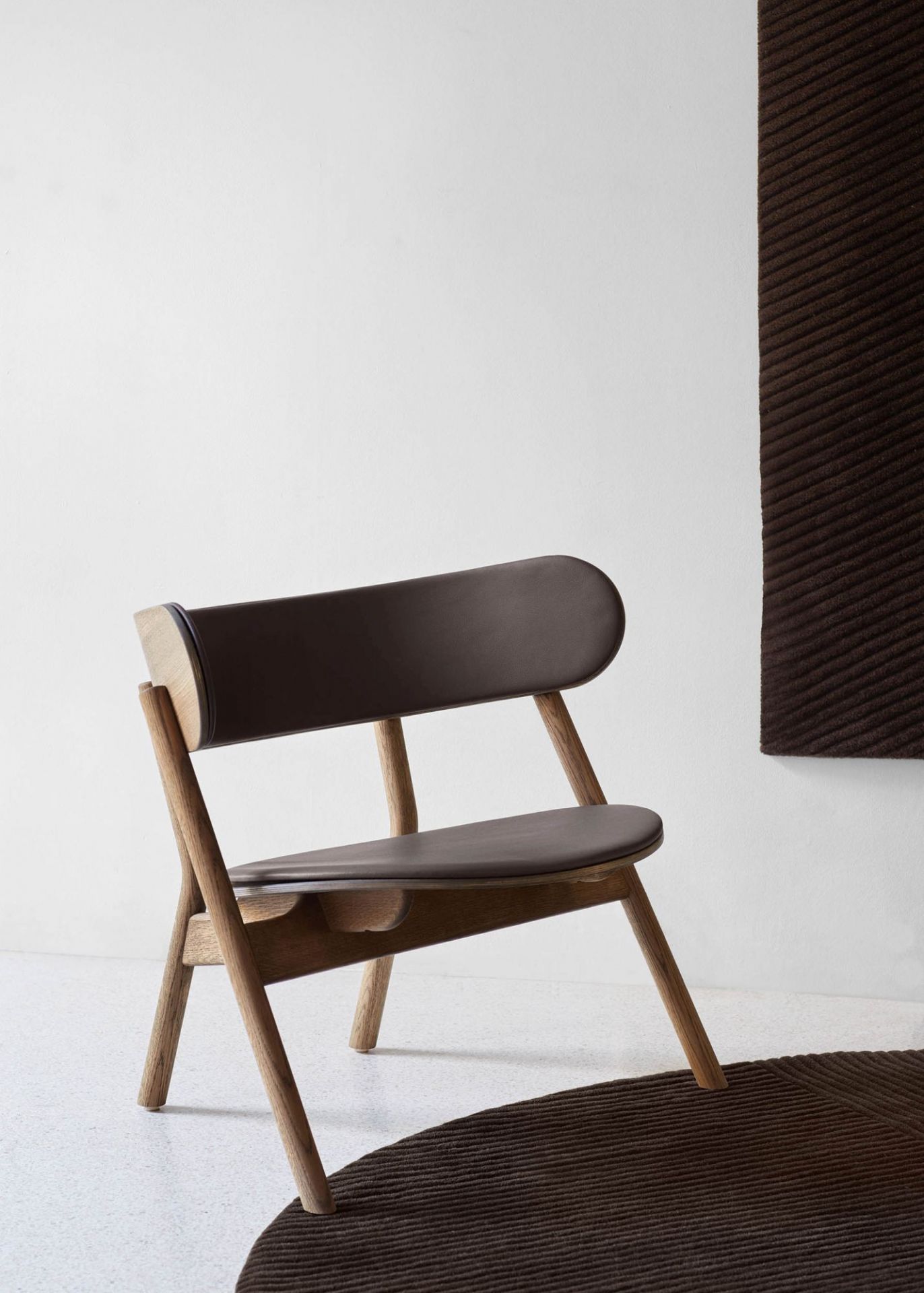 Oaki Lounge Chair mit brauner Polsterung. Moderner Sessel aus Holz und Leder.