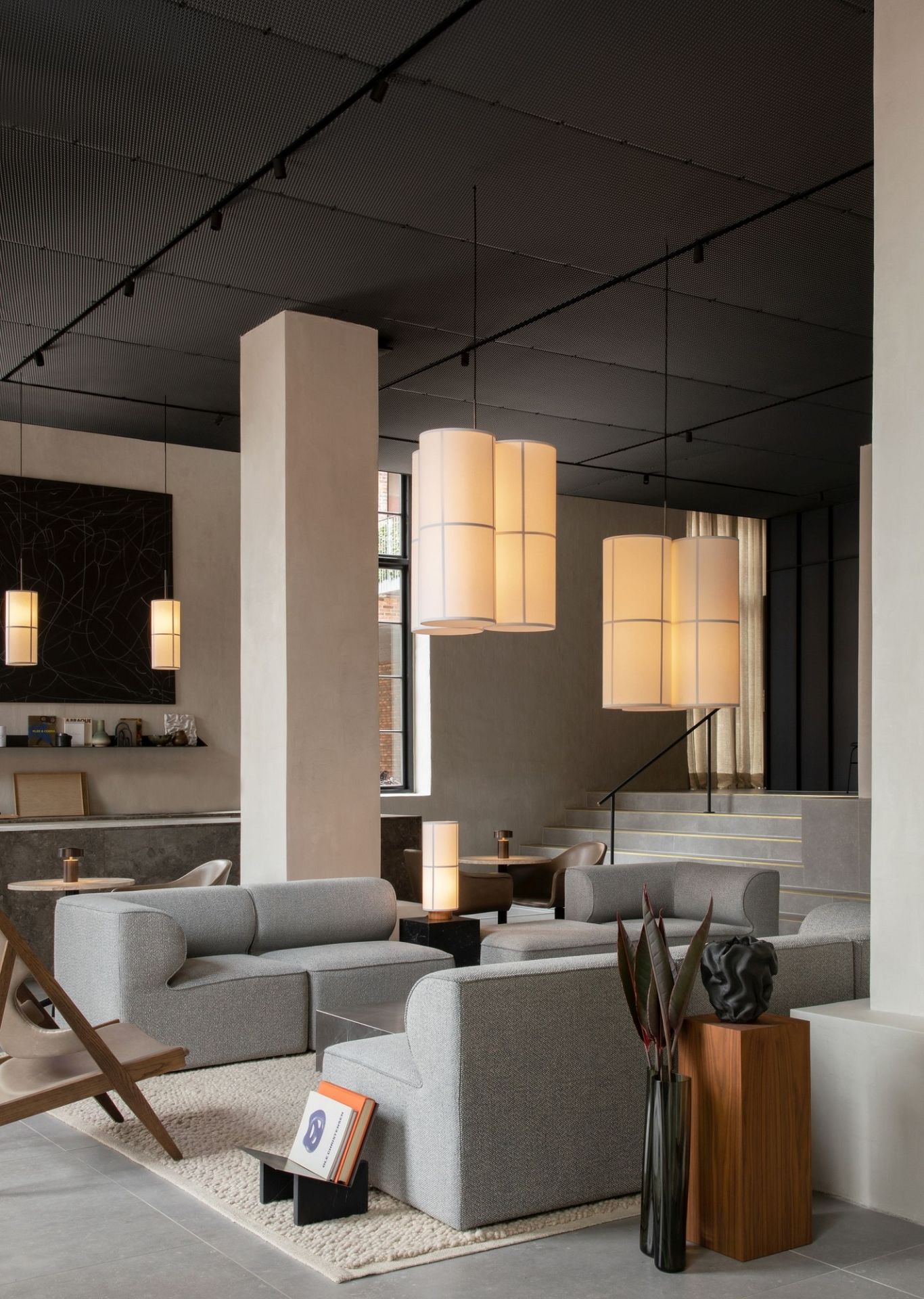 Audo Copenhagen Gravel Rug Teppich in einem modernen Wohnzimmer mit grauen Sofas und stilvoller Dekoration.