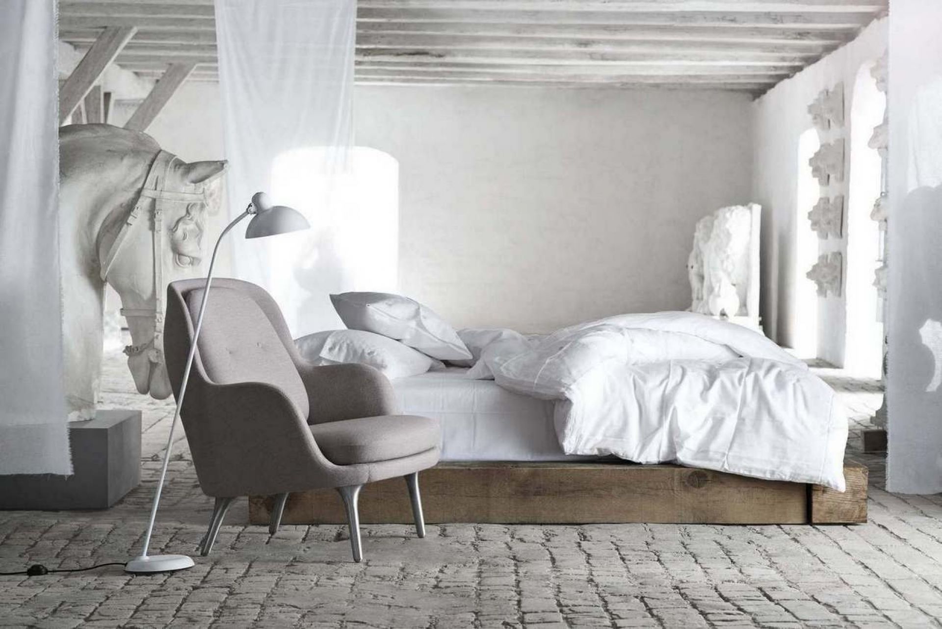 Fri Sessel von Fritz Hansen in grau mit Stehlampe und Bett im minimalistischen Interieur.