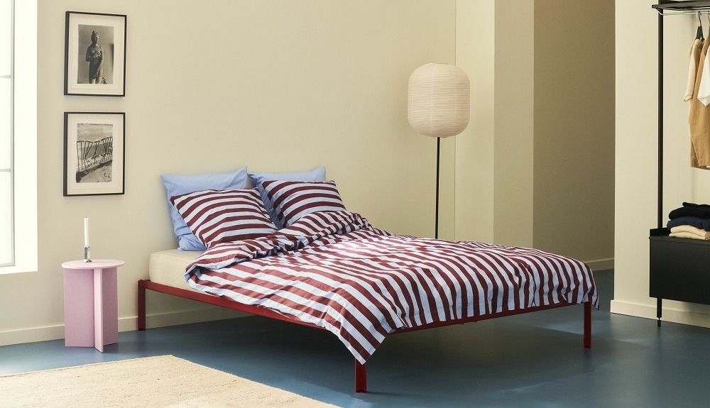 Rotes Connect Bed Bett von Hay mit gestreifter Bettwäsche und blauen Kissen.