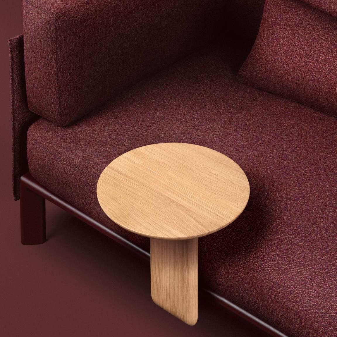 Anagram Anstecktisch von Vitra neben einem roten Sofa, runde Tischplatte aus hellem Holz.