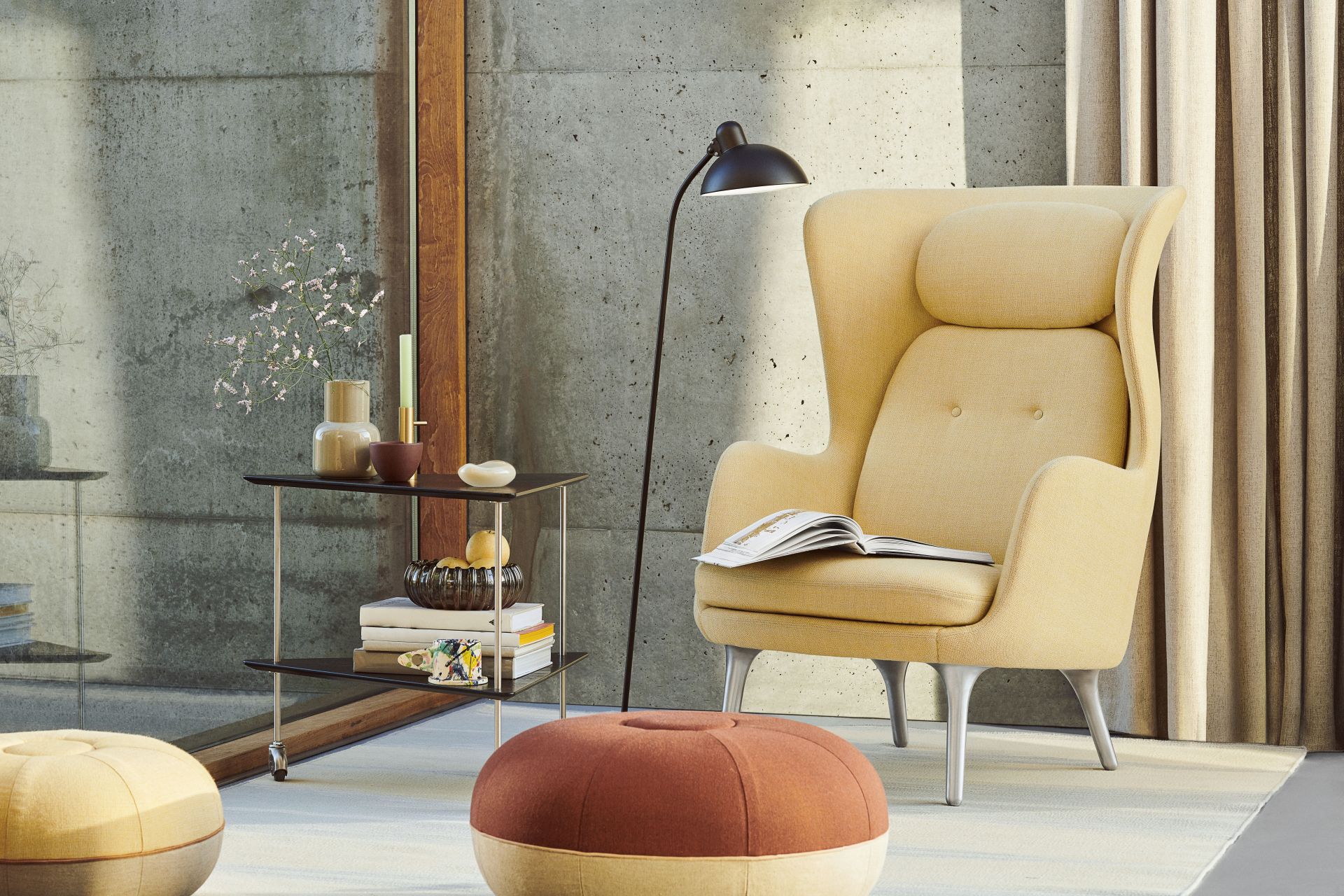 Beige Ro Sessel von Fritz Hansen mit Holzdetails und Buch im modernen Wohnzimmer.