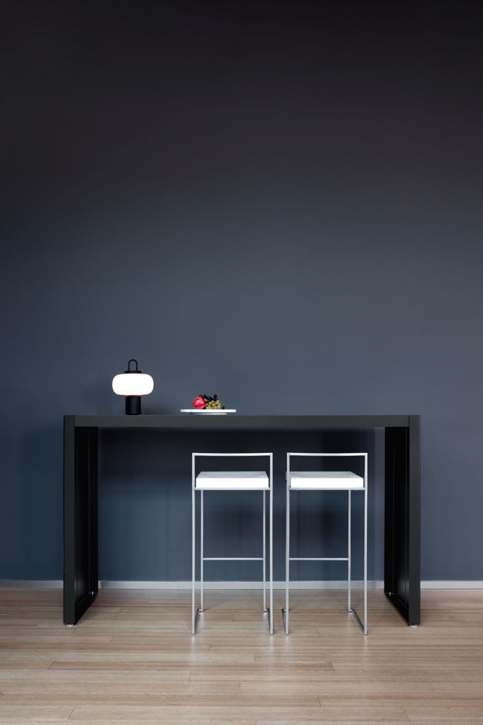 Zwei Cubo Barhocker mit weißer Sitzfläche und silbernem Gestell an einem schwarzen Bartisch.