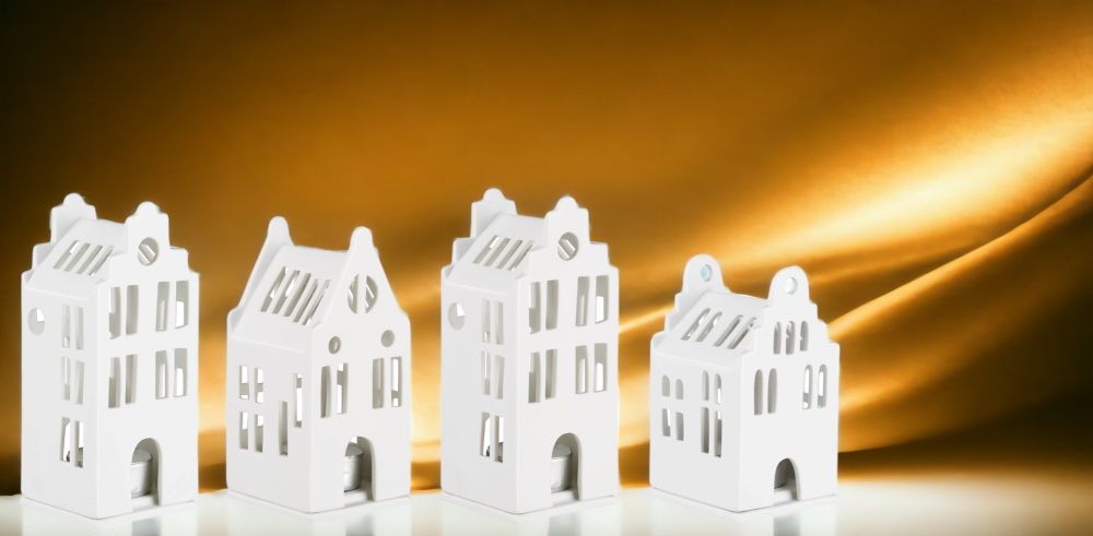 Vier weiße Lichthäuser im Grachtenhaus-Stil als Deko-Set für stimmungsvolle Beleuchtung im Zuhause.