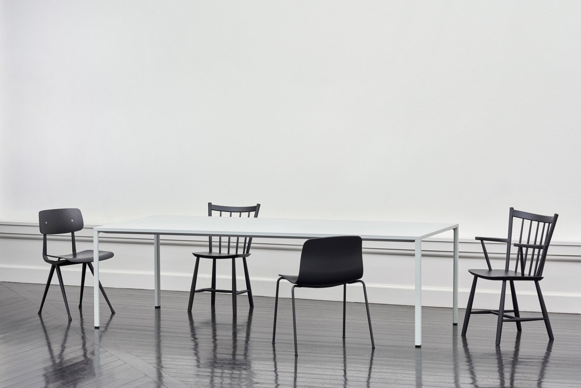 Esstisch mit vier verschiedenen schwarzen Stühlen, darunter ein About a Chair AAC16 Stuhl von Hay.