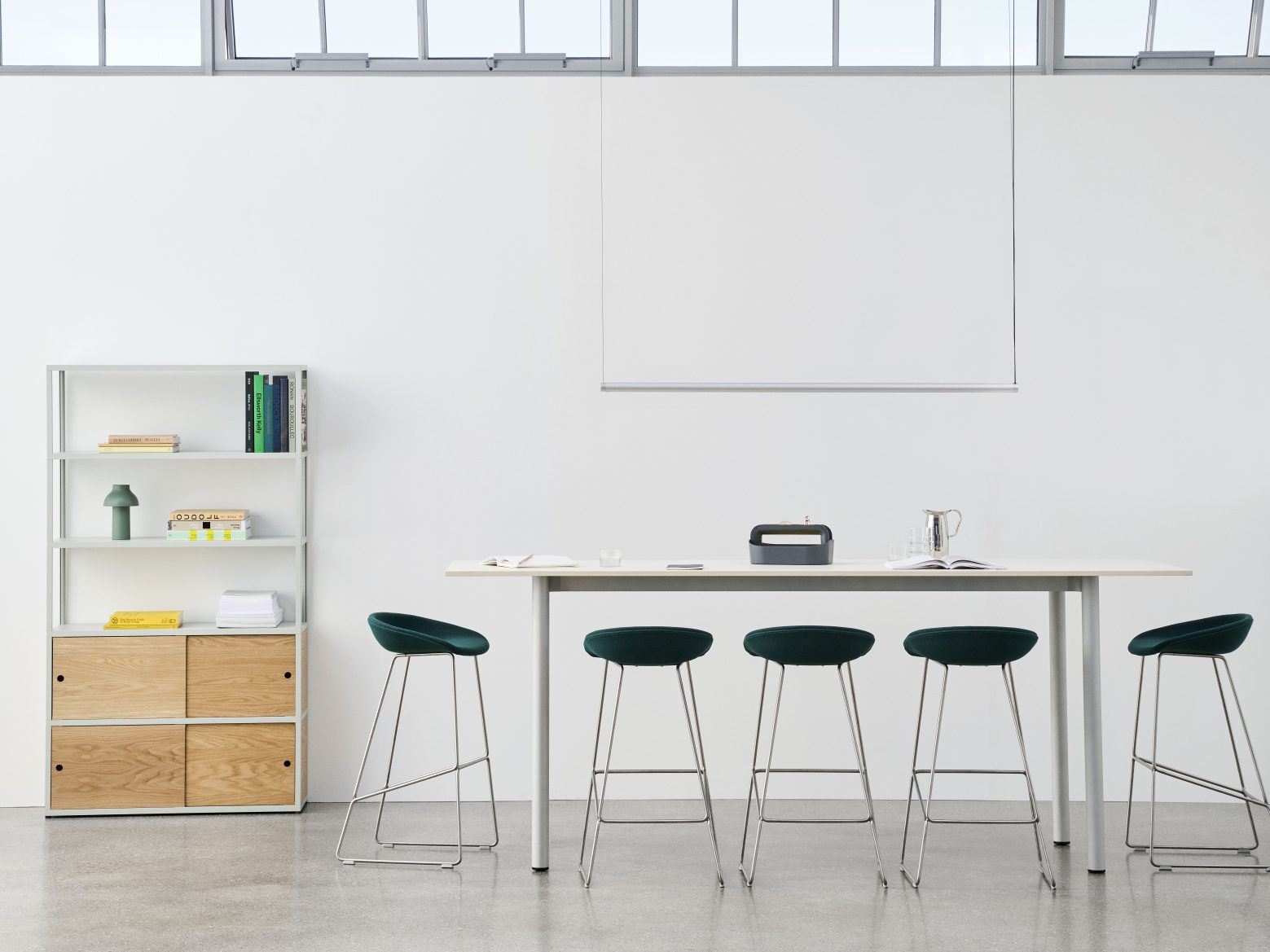 Annex Table Overhang Esstisch von Hay mit Barhockern in modernem Büroambiente und Bücherregal.