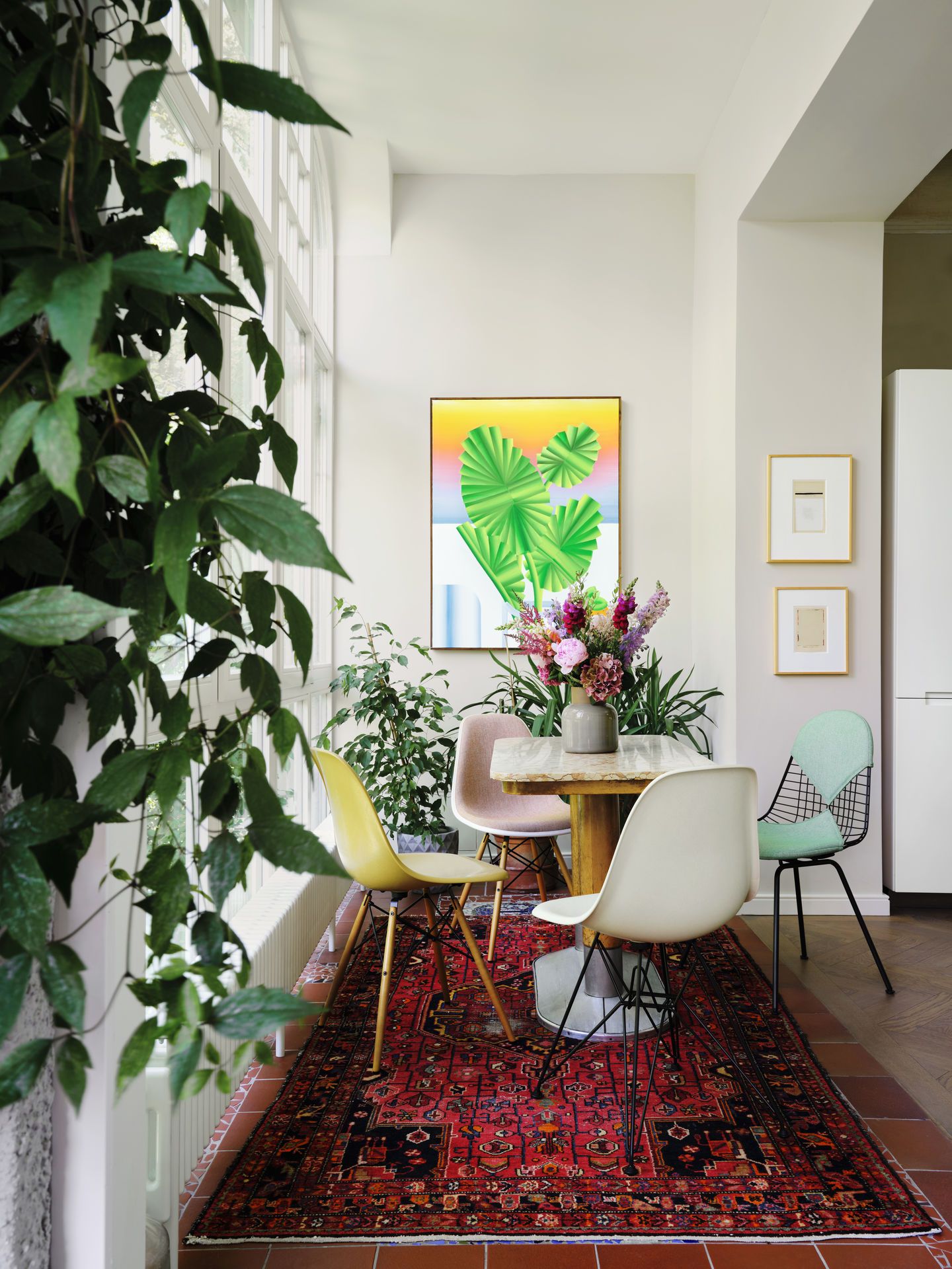 Esszimmer mit Vitra DKX Wire Chairs, gepolsterten Stühlen und einem Tisch auf einem roten Teppich.