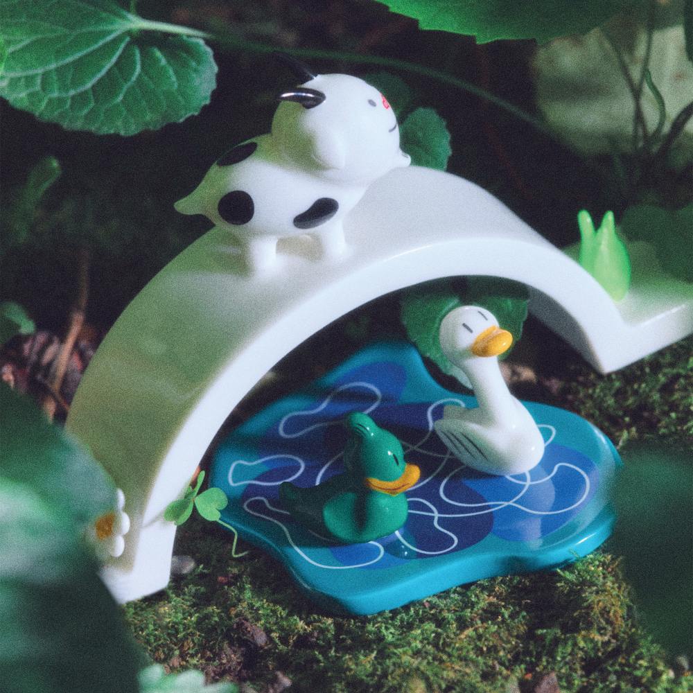 Happy Eternity Baby Brücke: Alessi Porzellanfigur mit Kuh und Enten auf blauem Teich.