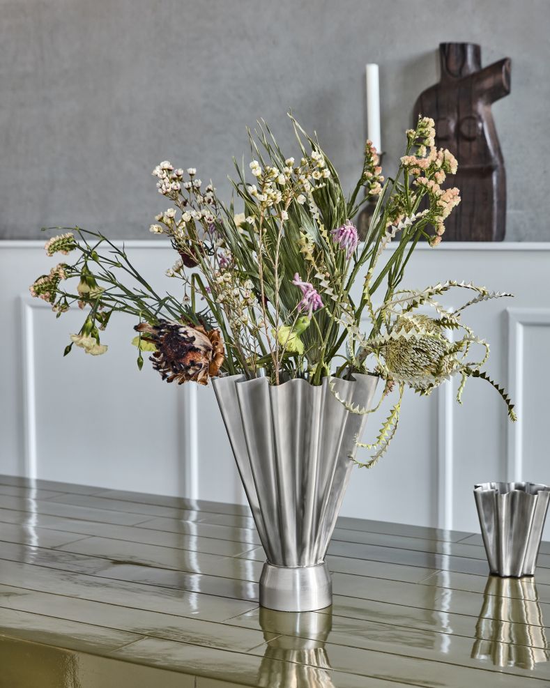 House Doctor Vase HDFlood Schmal mit gebürstetem Silber-Finish, gefüllt mit Trockenblumen auf einem Tisch.