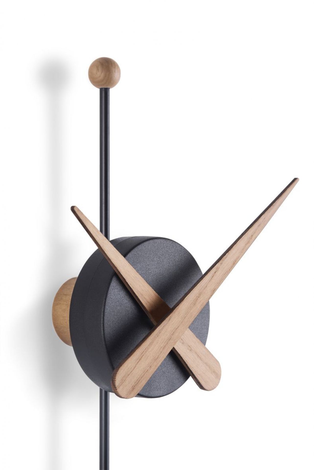 Detailaufnahme der modernen Punta Wanduhr von Nomon mit schwarzen Ziffernblatt und Holzzeigern.