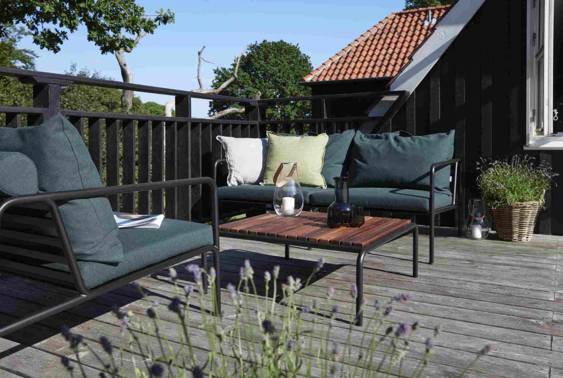 Avon 2-Sitzer Sofa von Houe auf Holzterrasse mit Kissen und Tisch, Outdoor-Möbel.