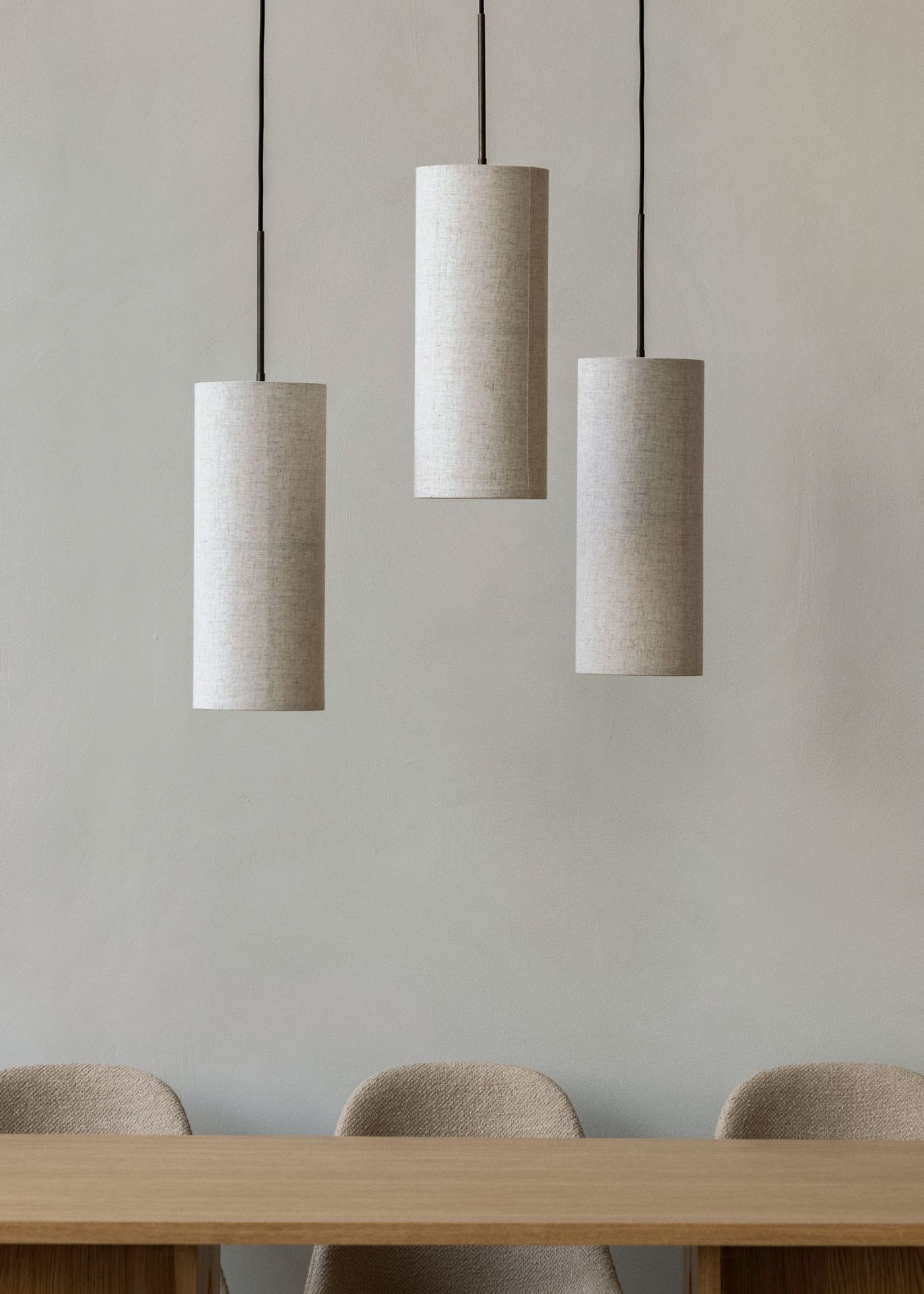 Drei weiße Hashira Pendelleuchten von Audo über einem Holztisch, moderne Innenraumbeleuchtung.