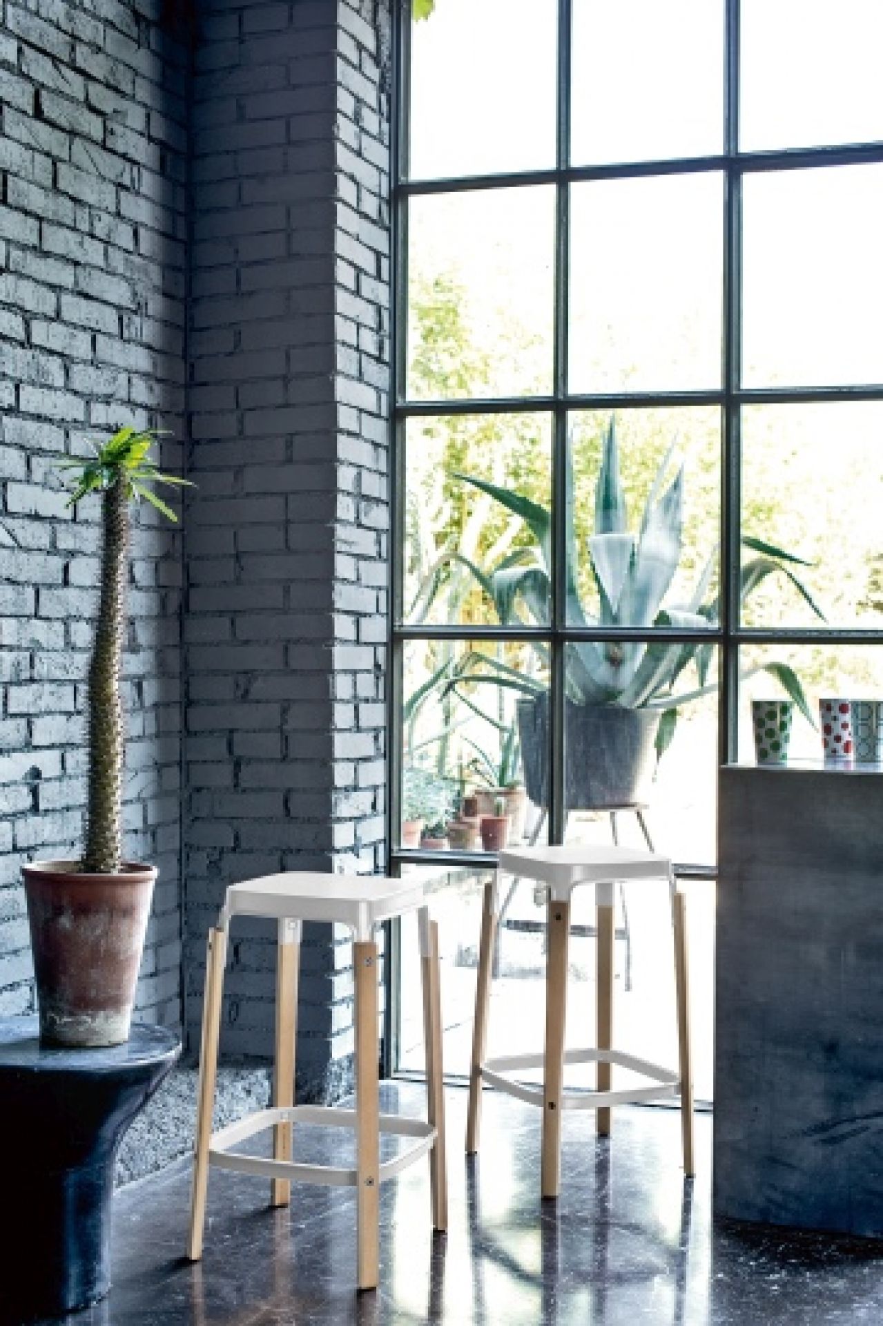 Zwei Steelwood Hocker von Magis, weißer Sitz und helle Holzbeine, im Interieur.