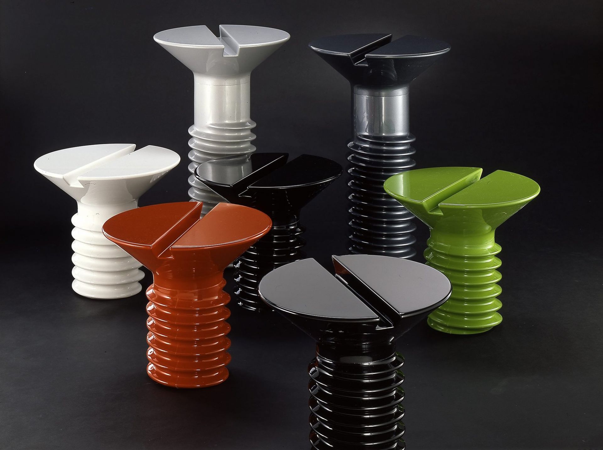 Mehrere Screw Tische von Eero Aarnio Originals in verschiedenen Farben, darunter Schwarz, auf schwarzem Hintergrund.