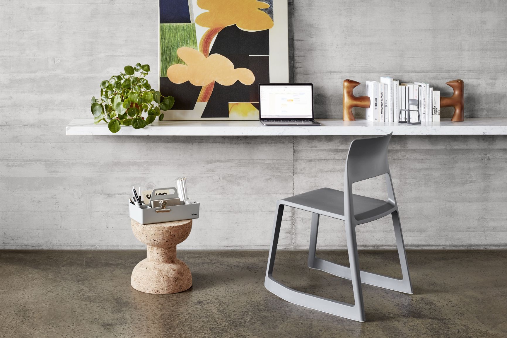 Büro-Szene mit grauem Stuhl, Schreibtisch mit Laptop, Vitra Girard Bird Skulptur und Deko-Elementen.