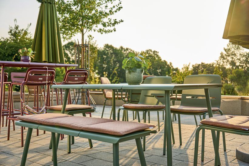 Weishäupl Vapio Tisch Outdoor mit Stühlen und Bank in Grün und Braun auf Terrasse.