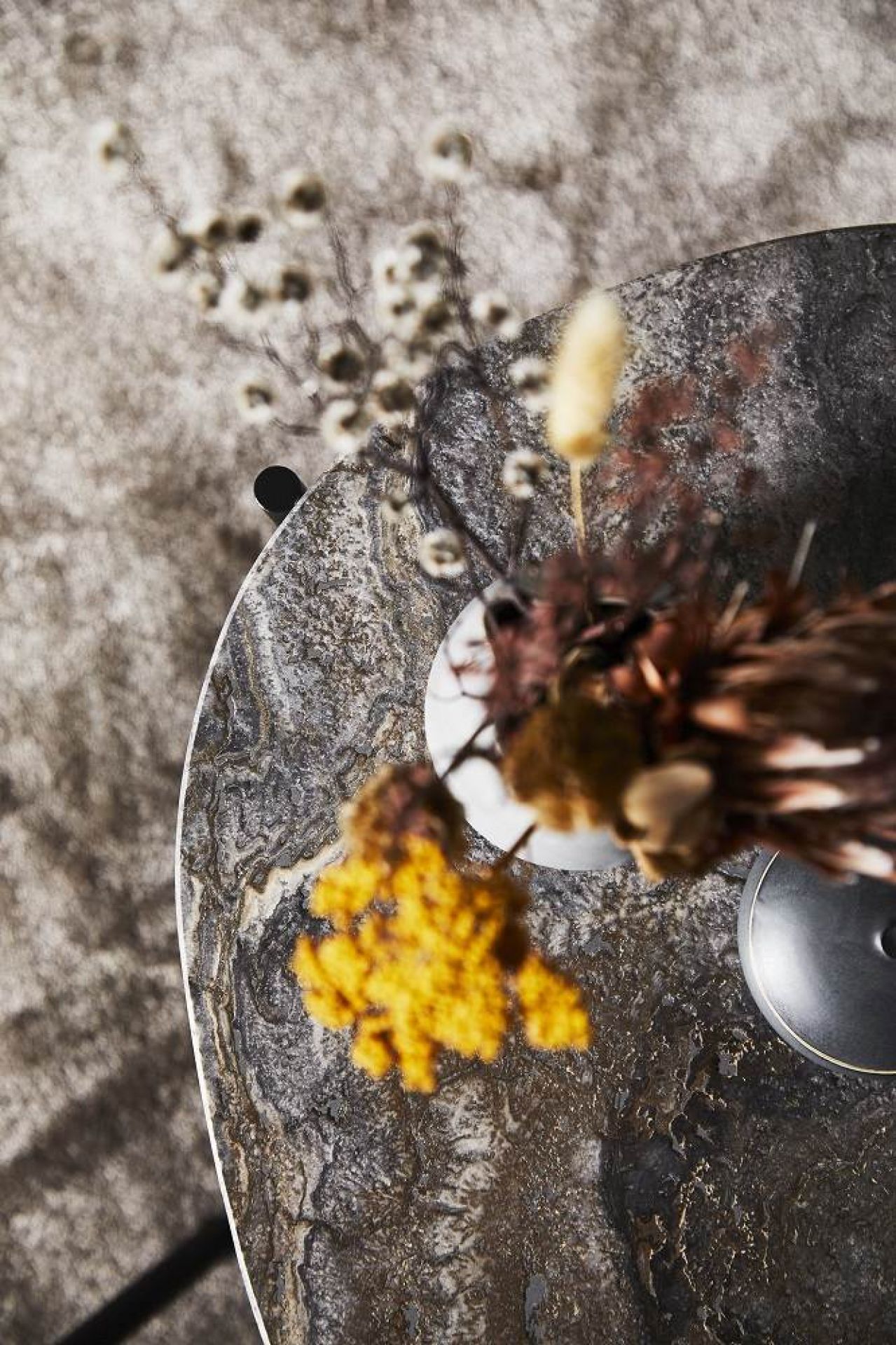 Draufsicht: La Terra Ocassional Couchtisch von Woud mit Blumen auf einer grauen Teppichoberfläche.