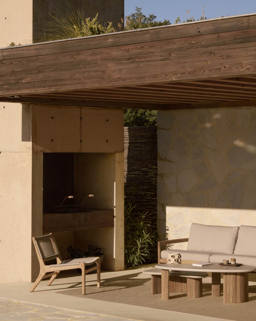 Ethnicraft Jack Outdoor Loungesessel aus Teak mit beiger Kordel und passendem Sofa auf Terrasse.