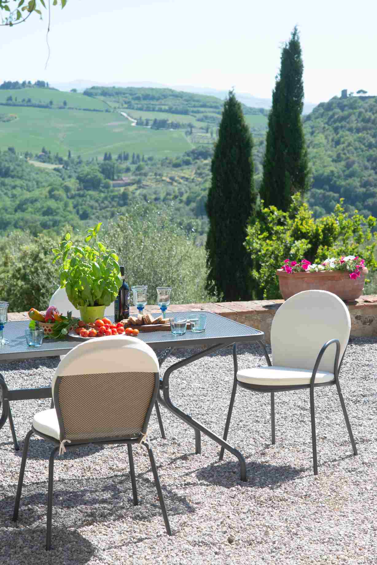 Emu Ronda Stuhl Outdoor: Gartenstuhl mit Sitzkissen und Metallgestell auf Kiesterrasse mit Esstisch.
