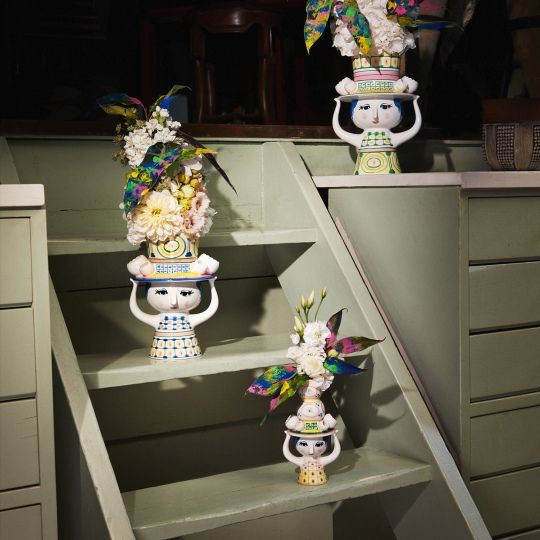 Drei Bjorn Wiinblad Lady with Hat Vasen auf einer grünen Treppe, gefüllt mit Blumen.