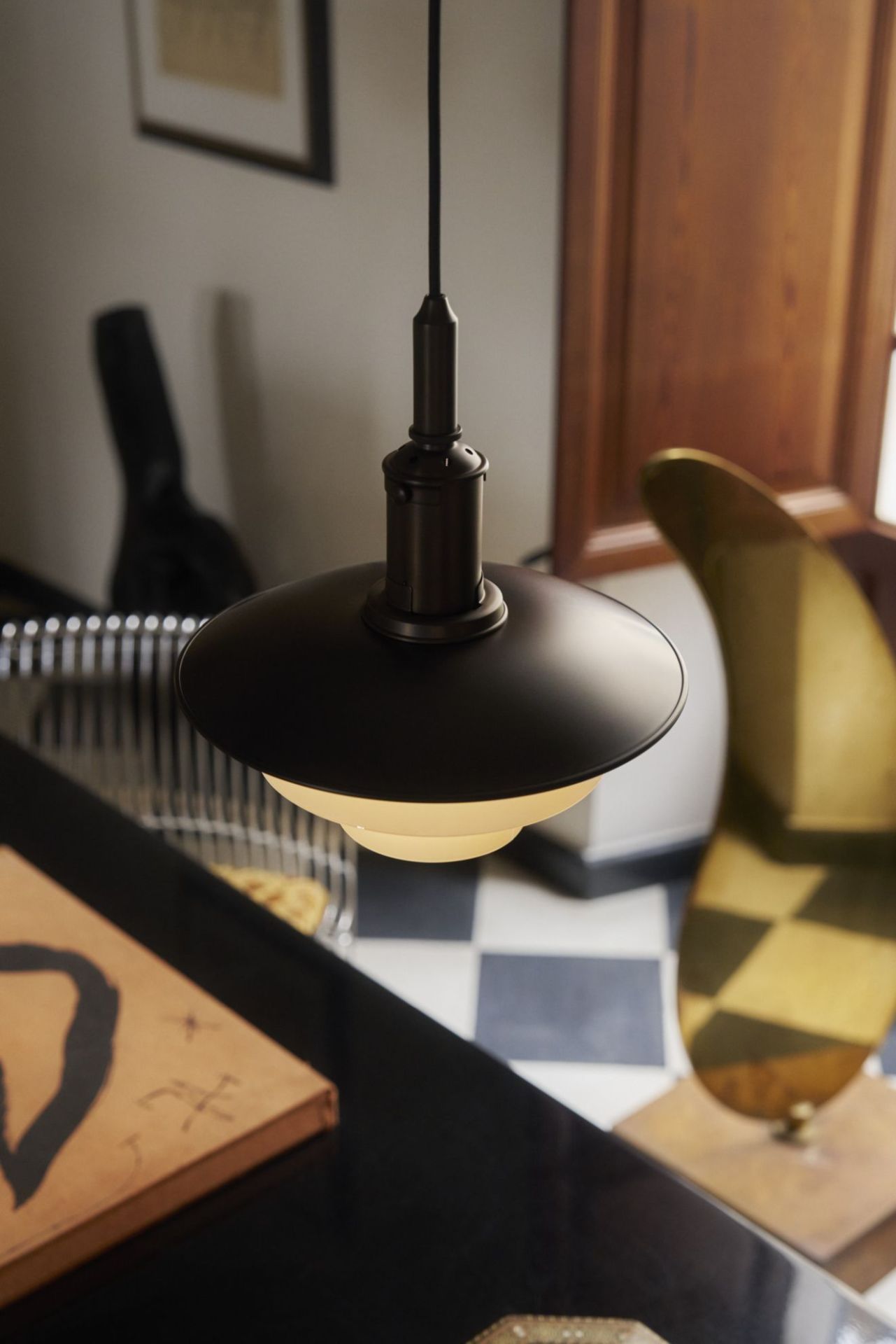 Nahaufnahme der Louis Poulsen PH 3/3 Pendelleuchte aus gealtertem Messing mit Opalglas, warmes Licht.