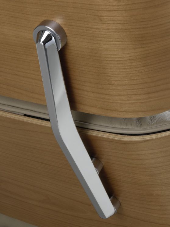 Detailaufnahme: Verchromter Armlehnen-Rahmen vom Eames Lounge Chair Sessel mit hellem Holzfurnier und Lederpolster.