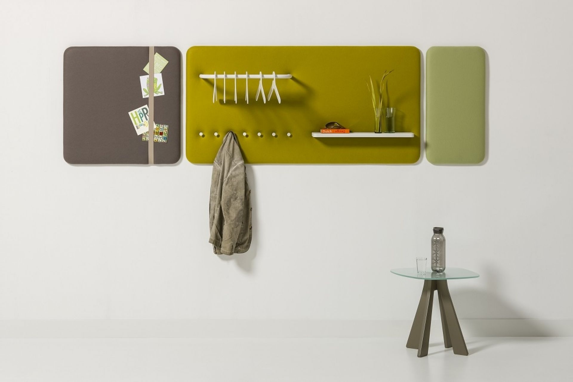 Cascando Pillow Wall Wandpaneele in Braun, Grün und Olivgrün mit Garderobenelementen und kleinem Tisch.