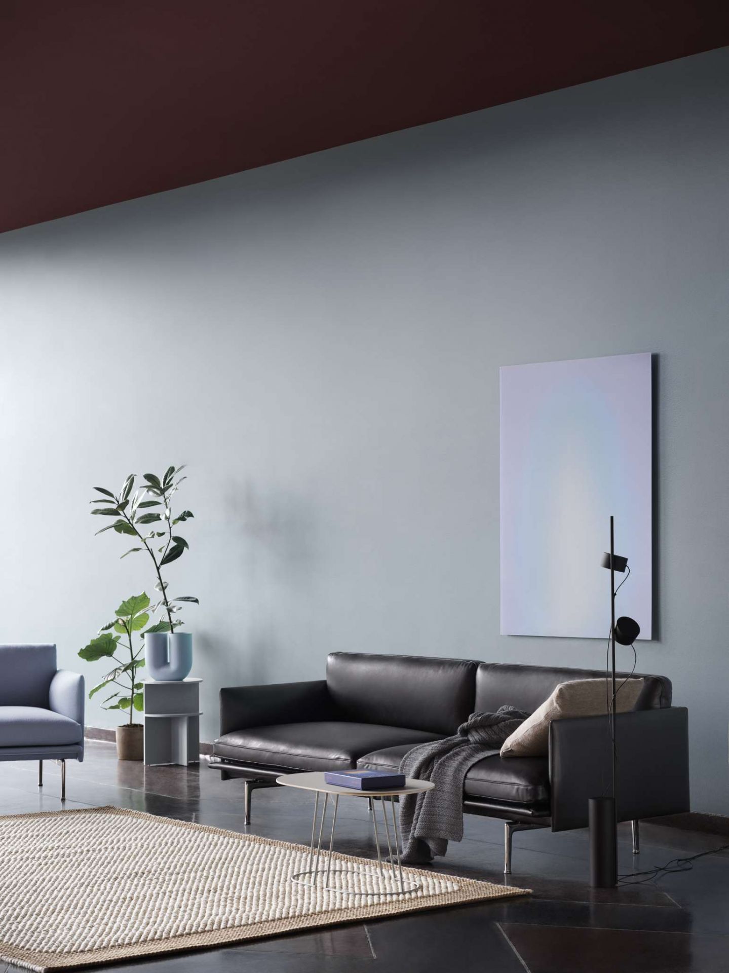 Wohnzimmer-Szene mit dunklem Ledersofa und grauer Ample Throw Decke von Muuto.