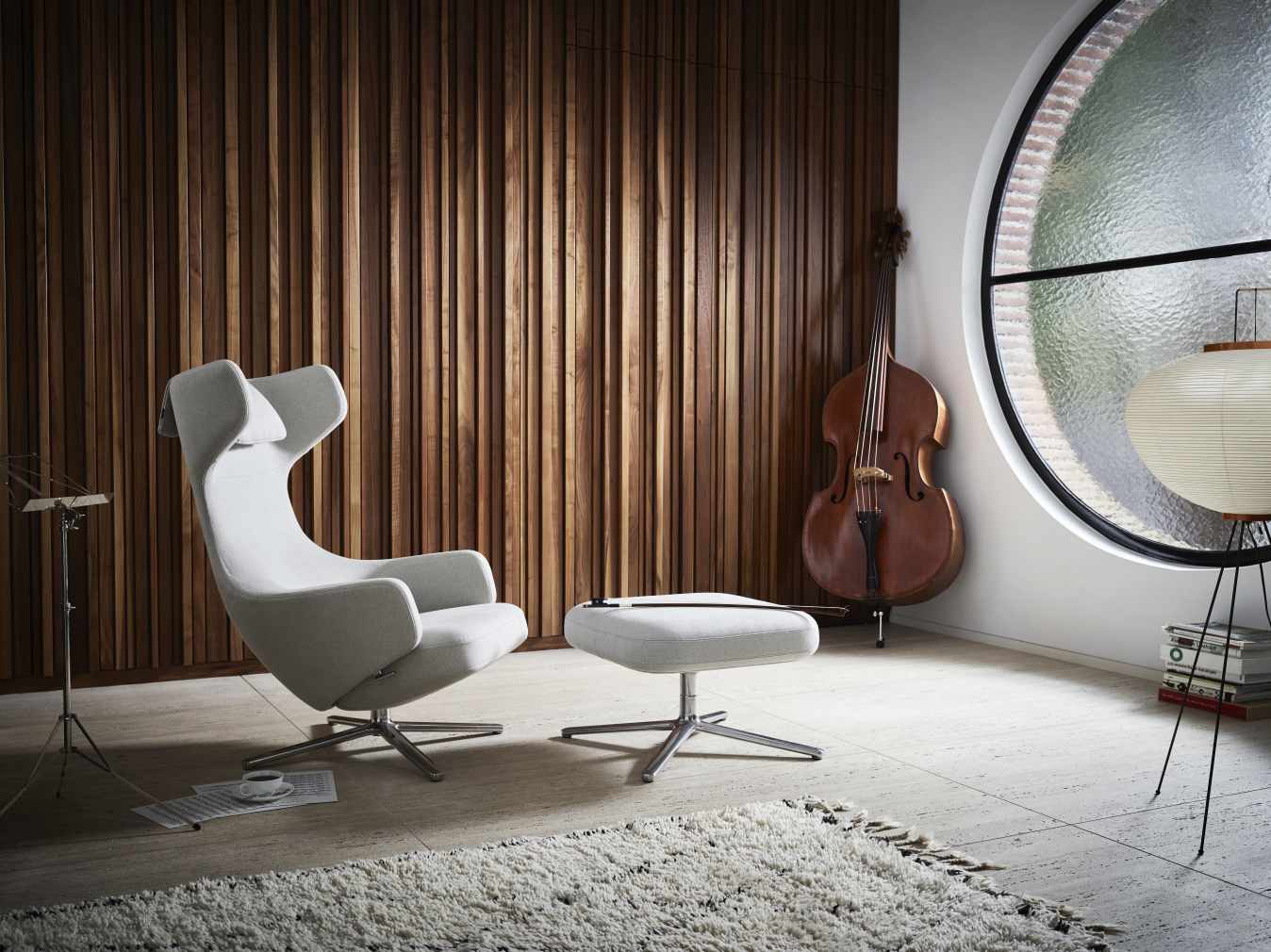 Grand Repos Sessel mit Ottoman von Vitra in Elfenbein und Perle vor Holzwand.