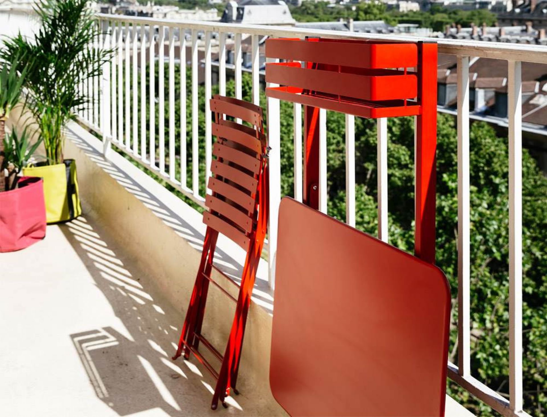 Roter Fermob Balkontisch und Stuhl für Outdoor Bistro, platzsparend am Balkongeländer befestigt.
