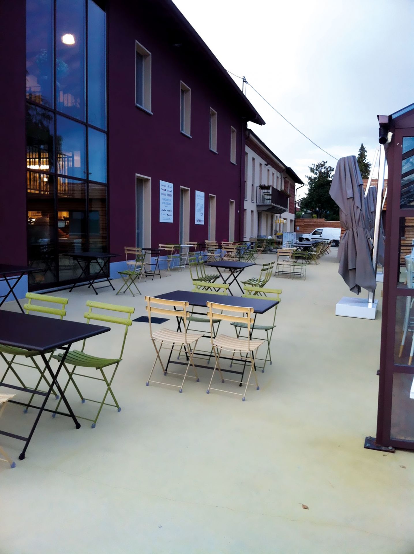 Außenbereich mit Tischen und Arc en Ciel Stühlen von emu in verschiedenen Farben für Garten und Terrasse.