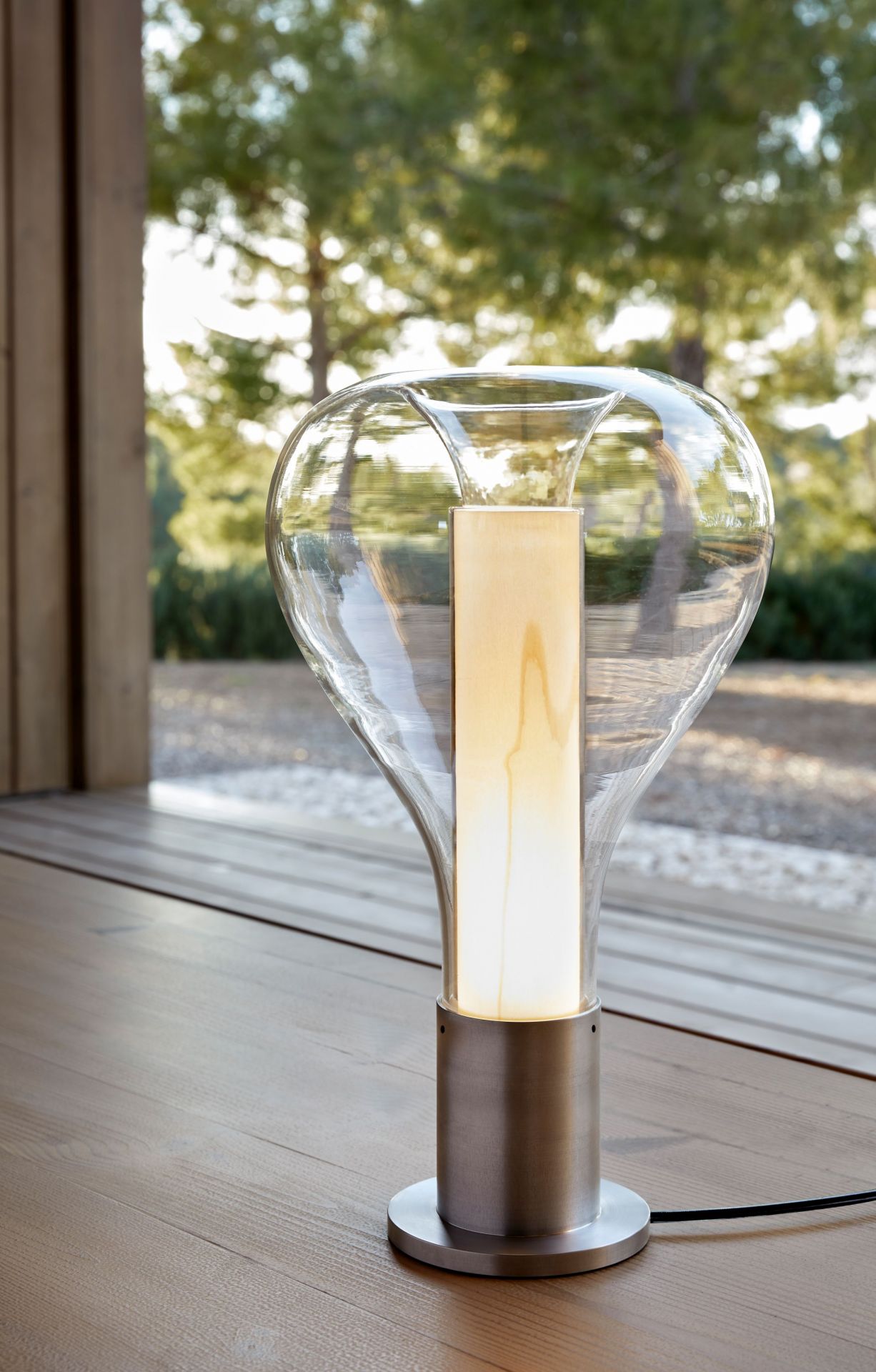 Eris Tischleuchte von LZF Lamps mit Aluminiumsockel und hellrosa Schirm auf Holztisch.