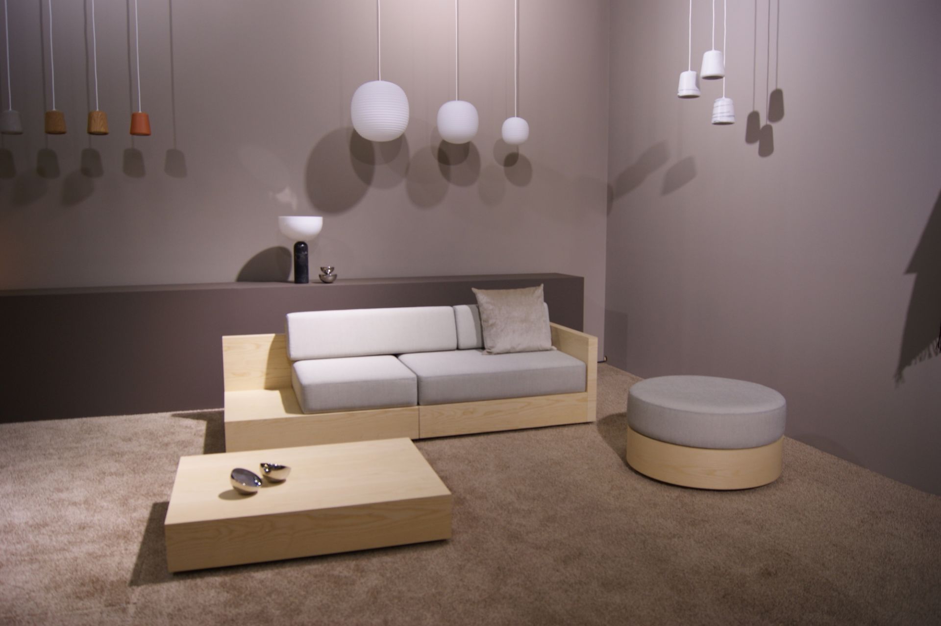 New Works Lantern Pendant Pendelleuchten in verschiedenen Formen und Farben über modernem Wohnzimmer mit Sofa.