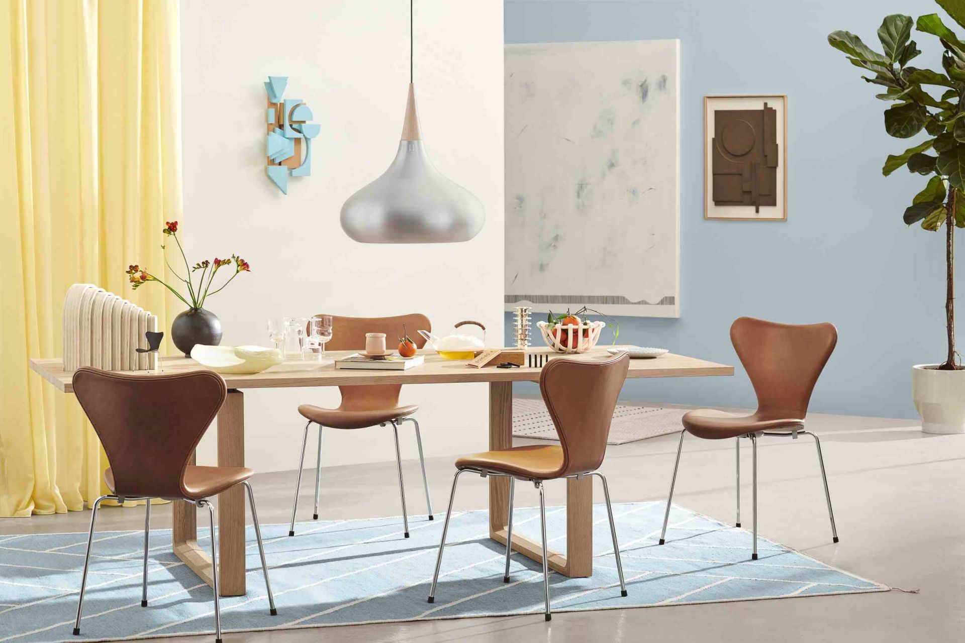Esszimmer mit Fritz Hansen Essay Tisch aus Eiche und braunen Stühlen auf blauem Teppich.
