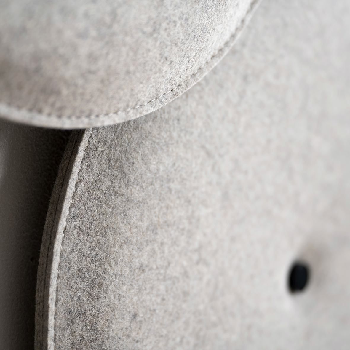 Detailaufnahme des grauen HEY-SIGN Akustik Wandelements aus Filz mit Knopf und feiner Naht.