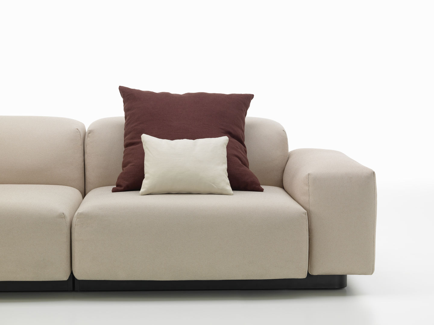 Beige Couch mit braunem und weißem Vitra Kissen / Sofakissen für Wohnzimmer und Lounge.