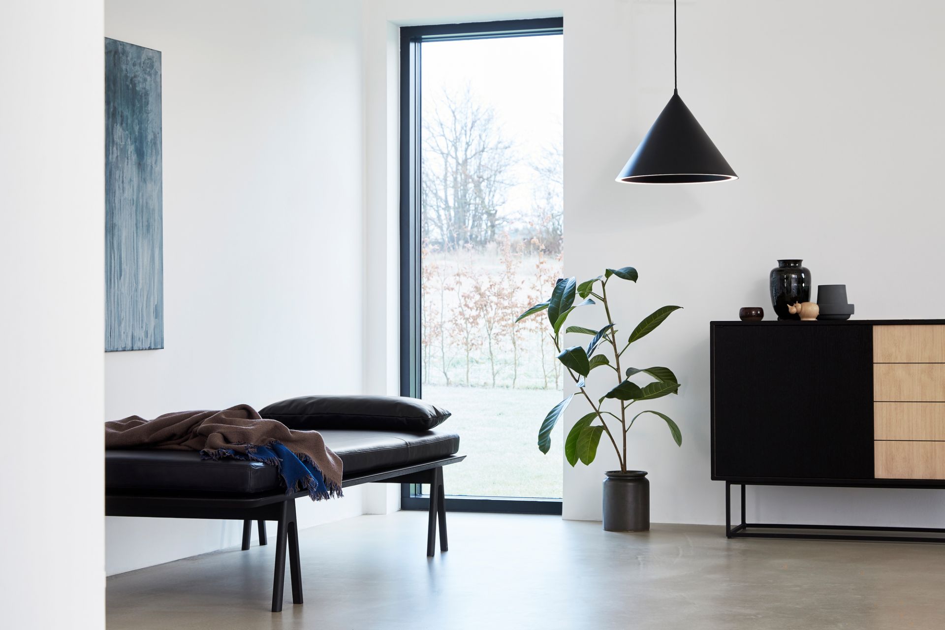 Helles Interieur mit schwarzer Level Daybed Liege von Woud, Decke, Kissen und Kommode mit Dekoration.
