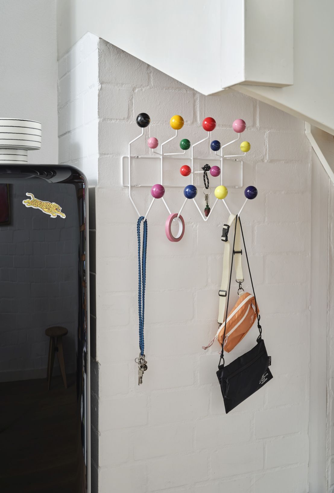 Eames Hang it all Garderobe mit bunten Kugeln an weißer Wand, Taschen und Schlüssel hängen.