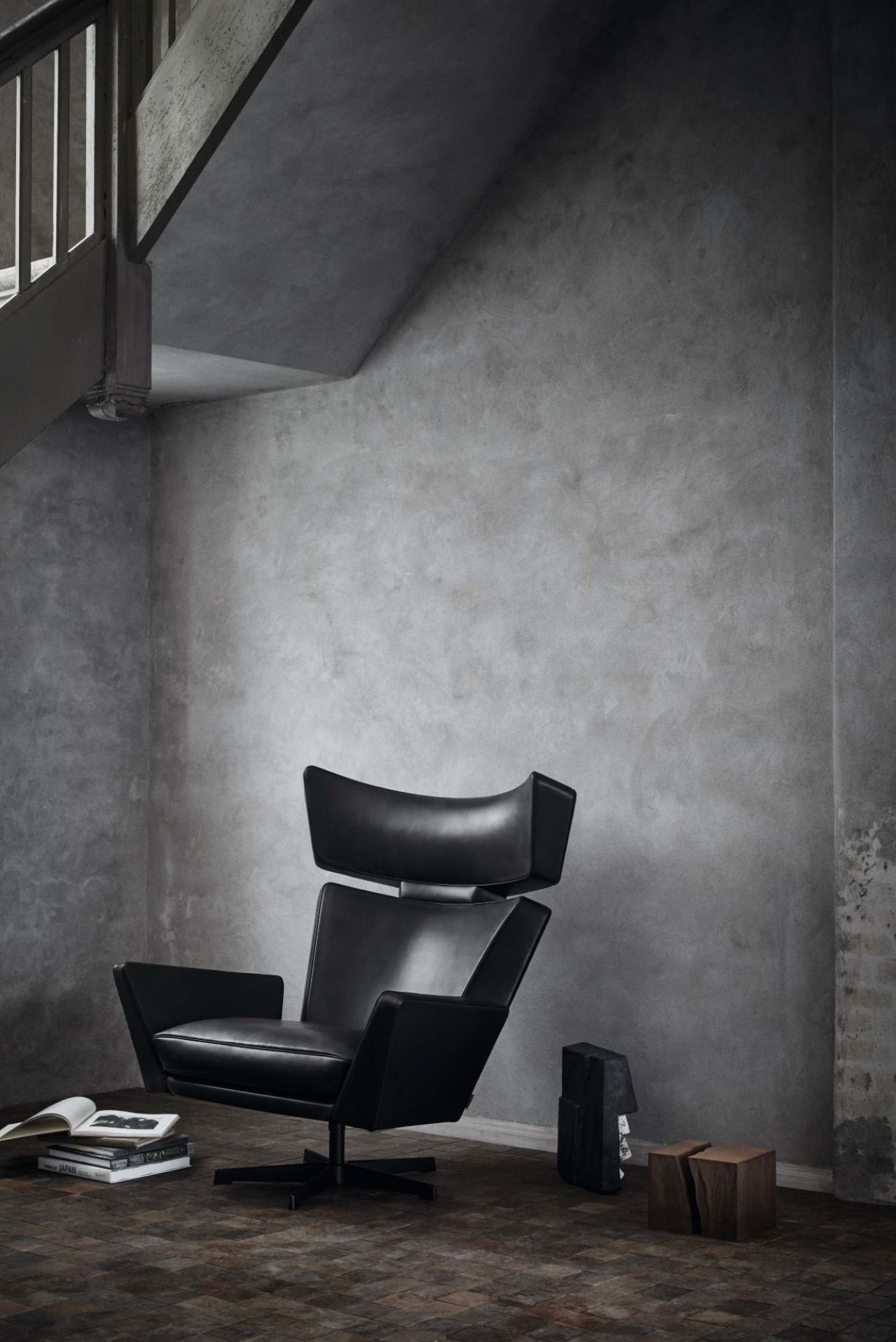 Schwarzer Oksen Sessel von Fritz Hansen im Interieur mit Betonwand und Holzfußboden.