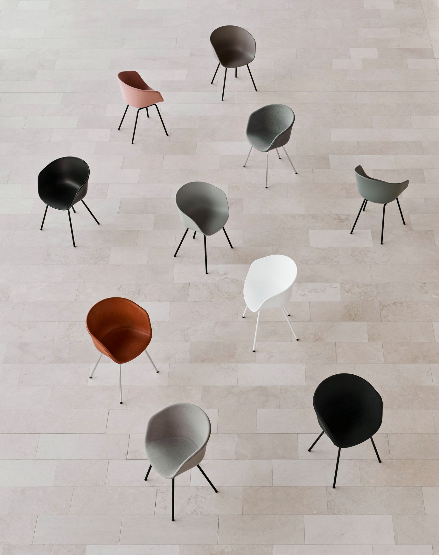 Draufsicht von mehreren Hay About A Chair AAC26 Stühlen in verschiedenen Farben auf einem hellen Fliesenboden.