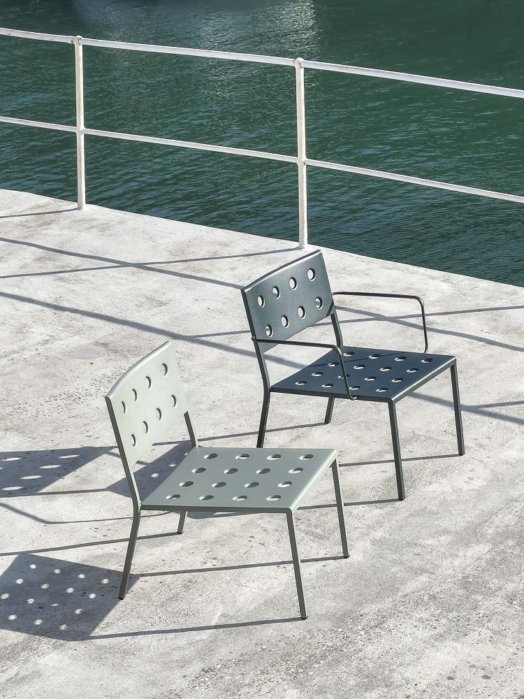 Zwei Hay Balcony Outdoor Lounge Stühle in Grau und Schwarz auf einer Terrasse am Wasser.