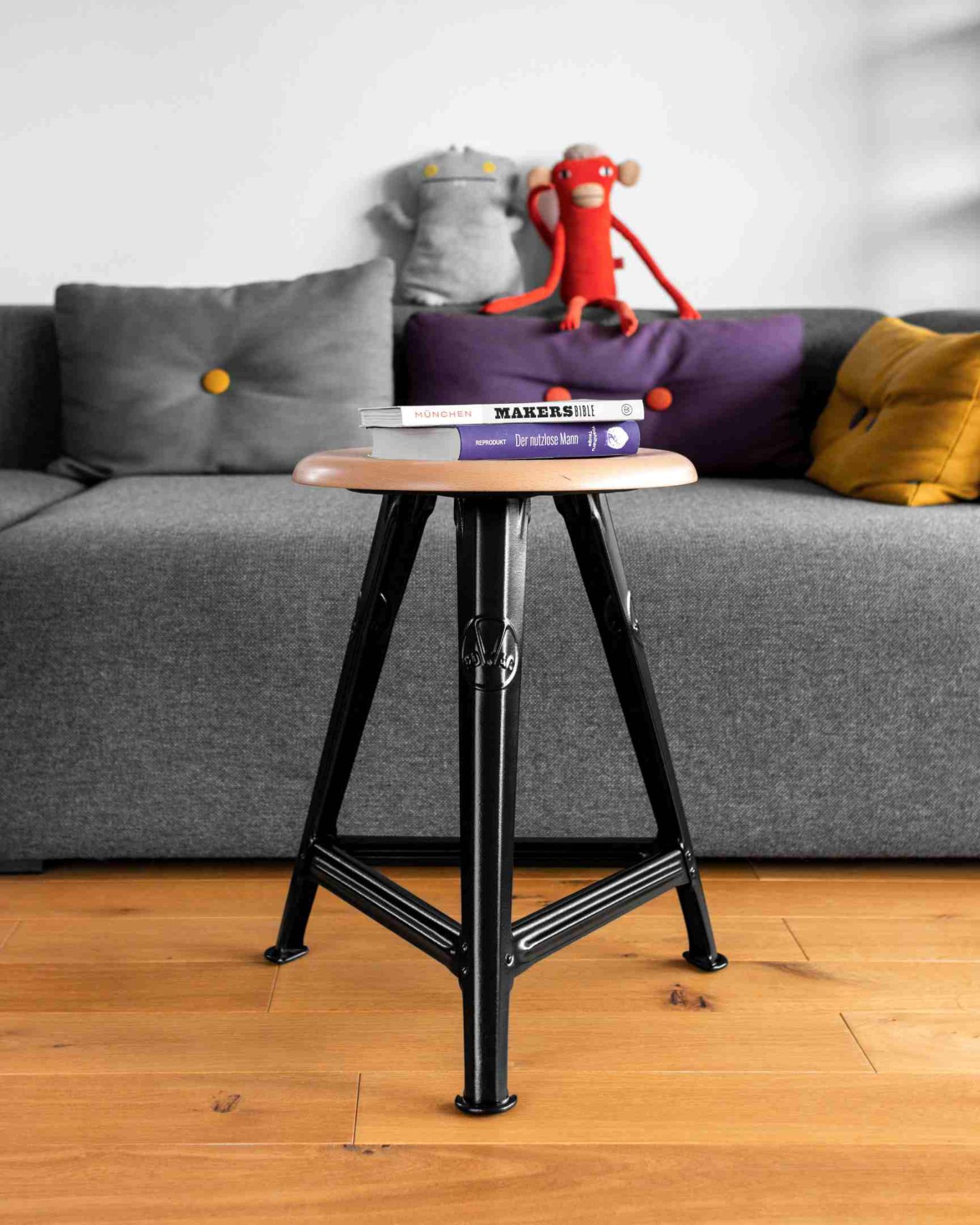 Schemel Model I Hocker 50 cm von Rowac, Holz-Sitzfläche und schwarzes Metallgestell im modernen Wohnzimmer.