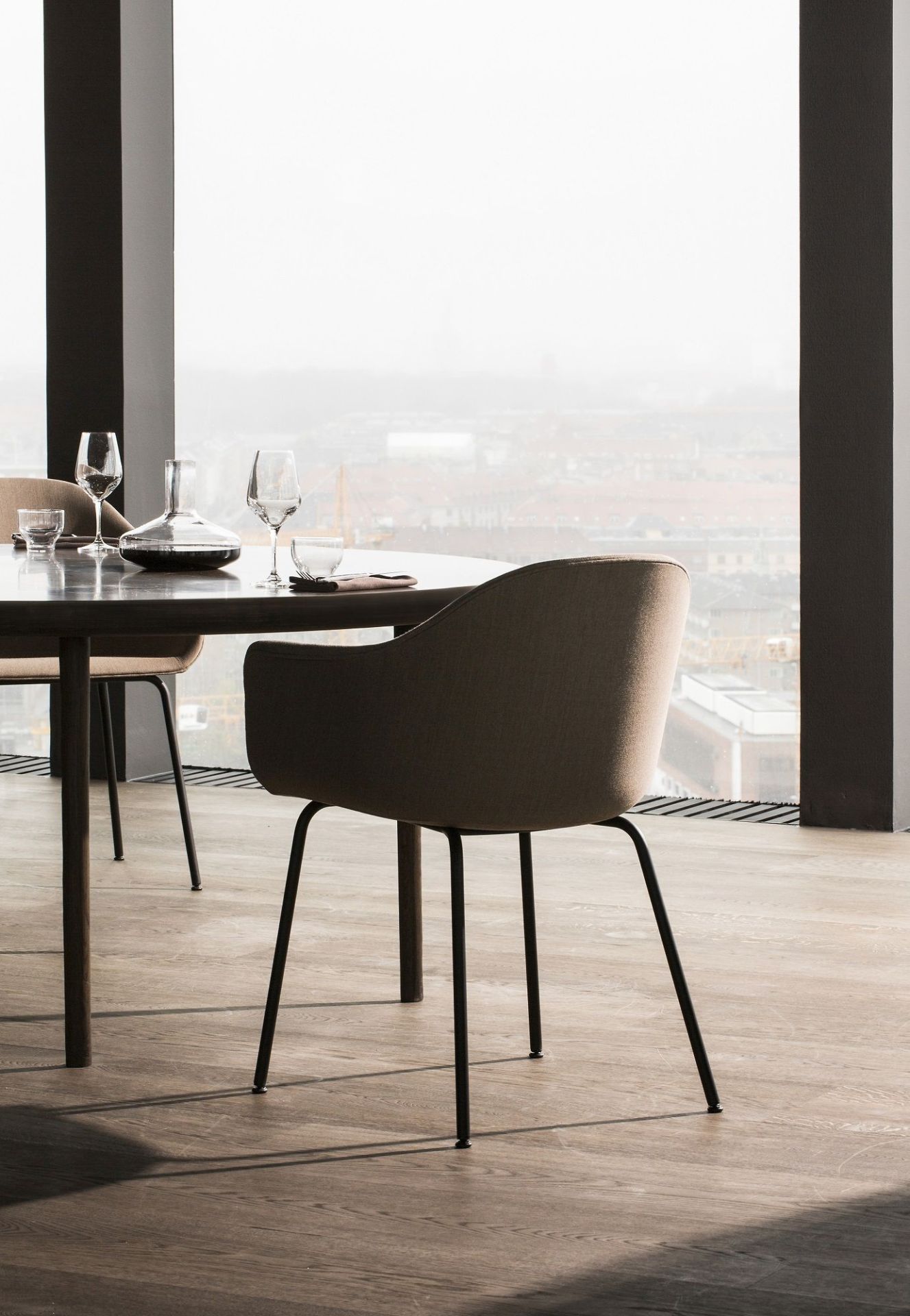 Audo Copenhagen Harbour Dining Chair Stuhl in Beige am Esstisch mit Blick auf die Stadt.