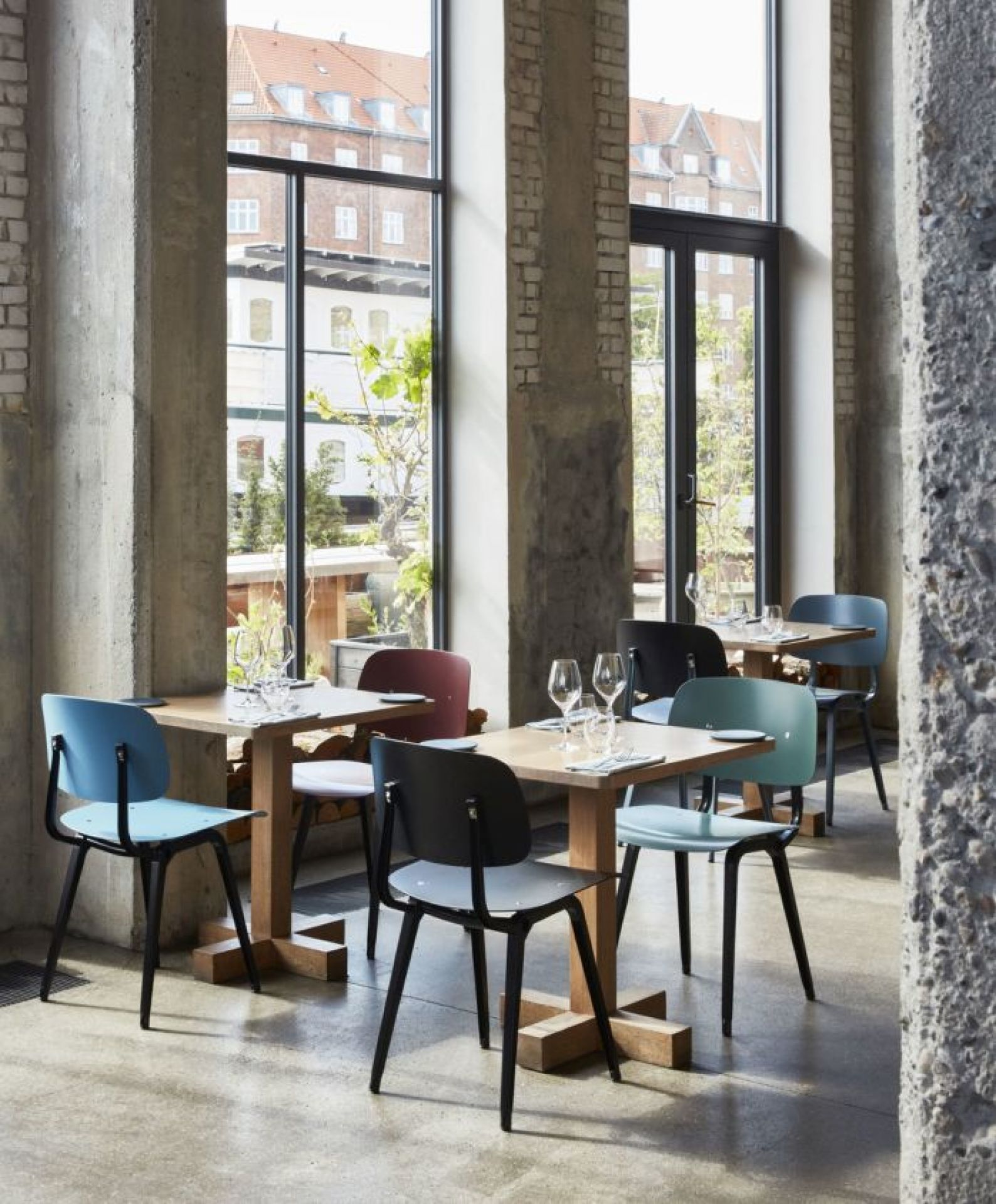 Innenansicht eines Restaurants mit mehreren Hay Revolt Stühlen in verschiedenen Farben an Holztischen.
