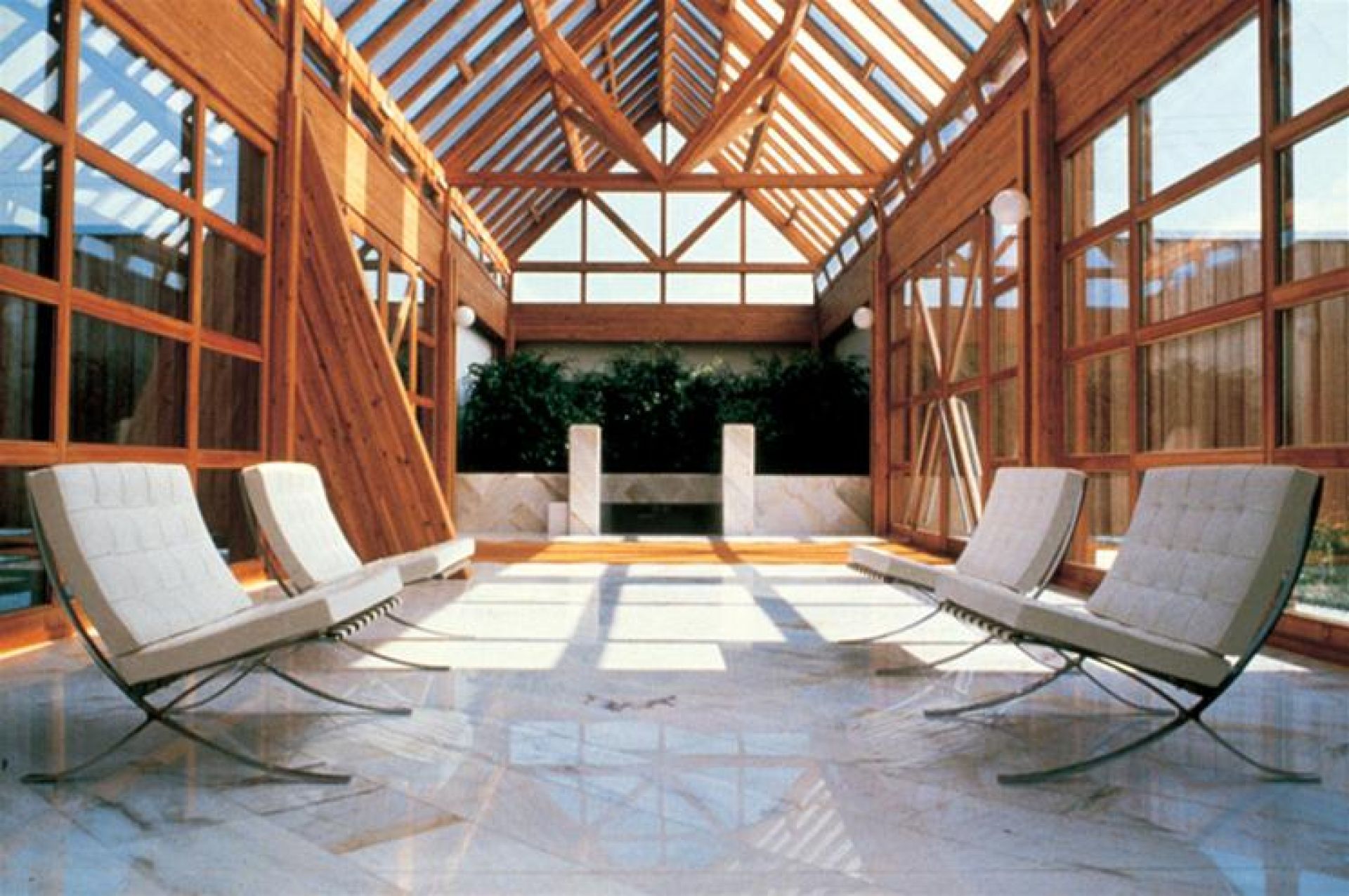 Barcelona Sessel von Knoll International in lichtdurchflutetem Raum mit Holzkonstruktion und Marmorboden.