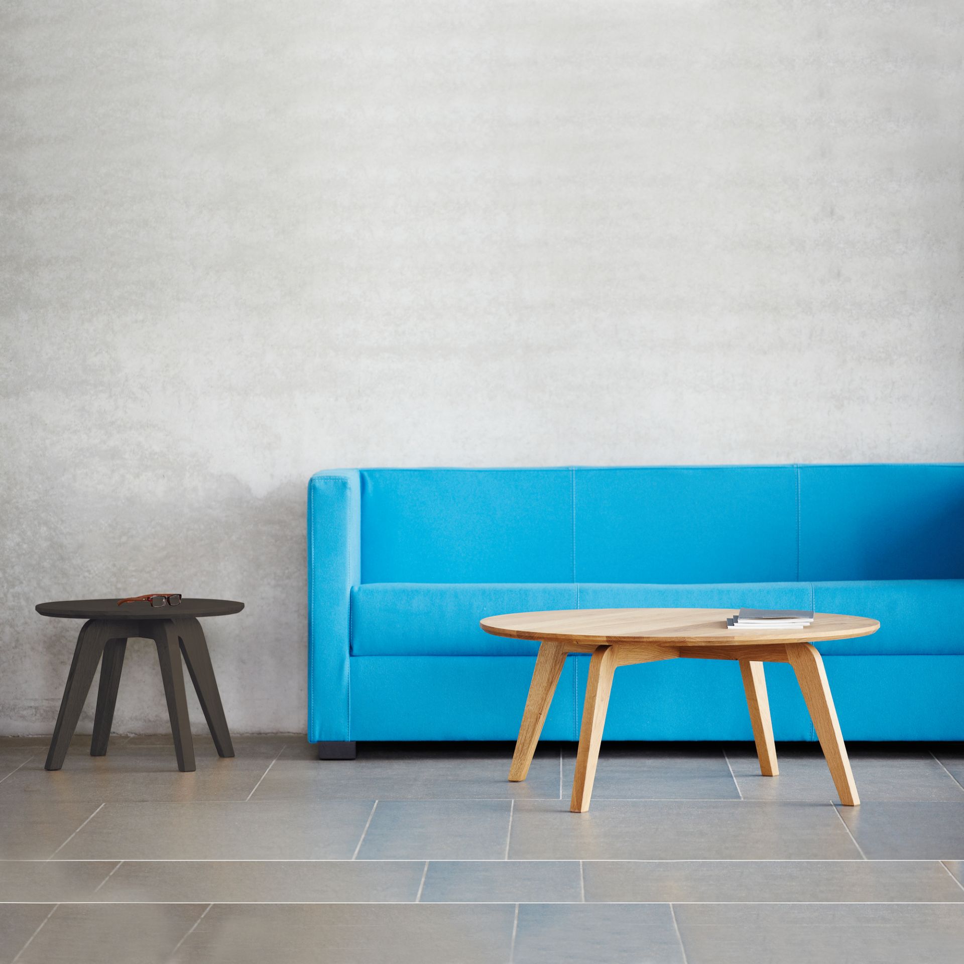 Dweller Couchtisch Natur von Jan Kurtz aus Holz, runder Wohnzimmertisch vor blauem Sofa.
