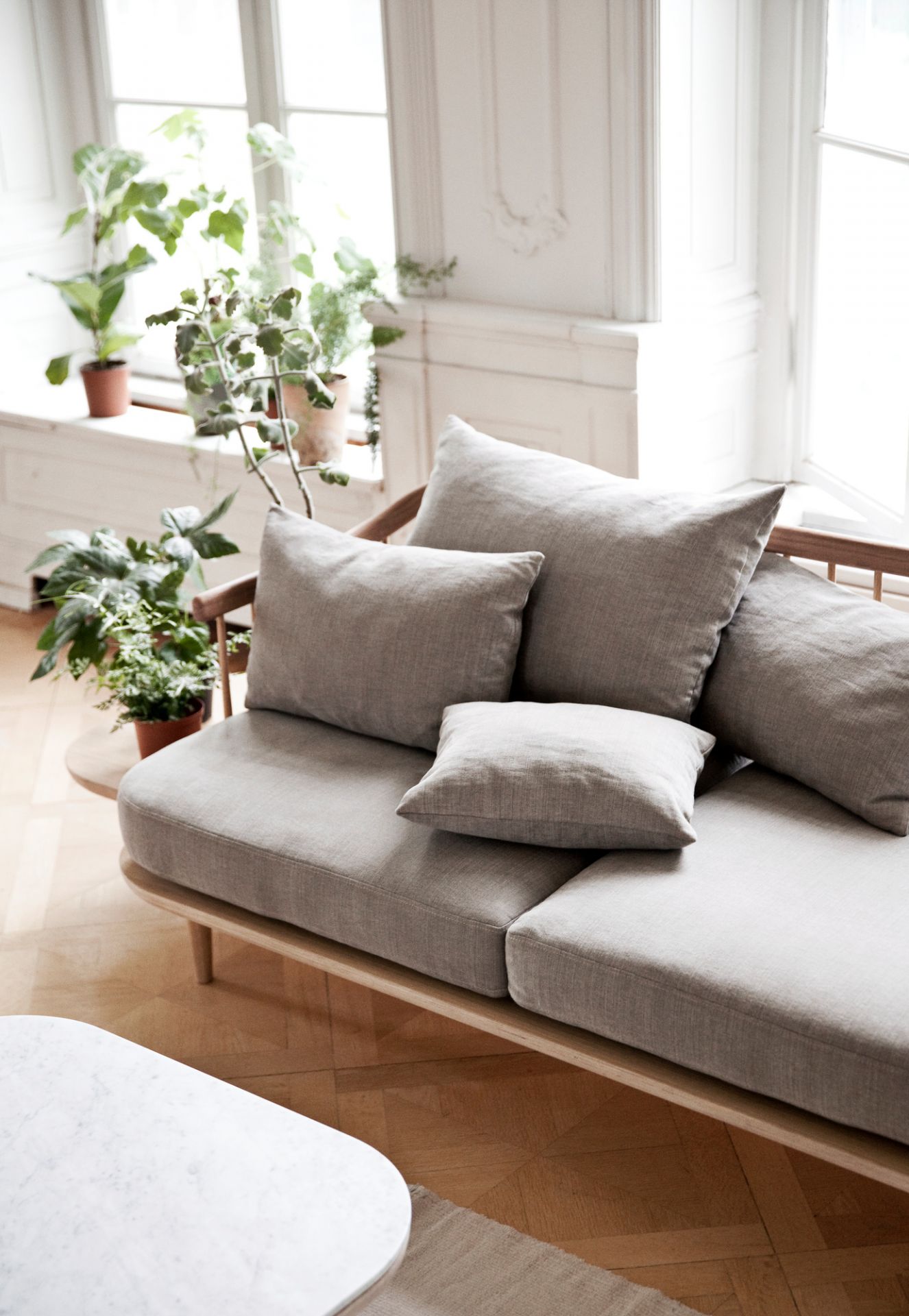 Fly Lounge 2-Sitzer Sofa von AndTradition mit Eichengestell und grauer Polsterung im hellen Wohnraum.