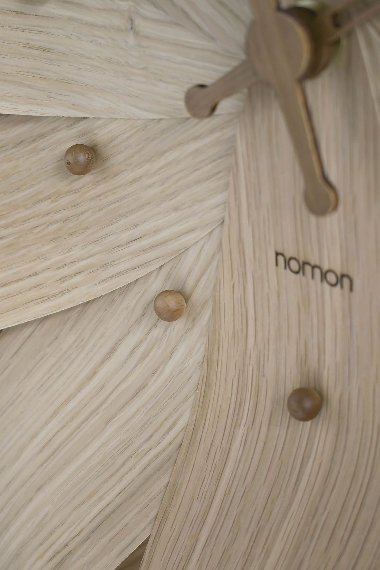 Detailaufnahme der Nomon Brisa Wanduhr aus Holz, modernes Design mit Holzzeigern und -details.