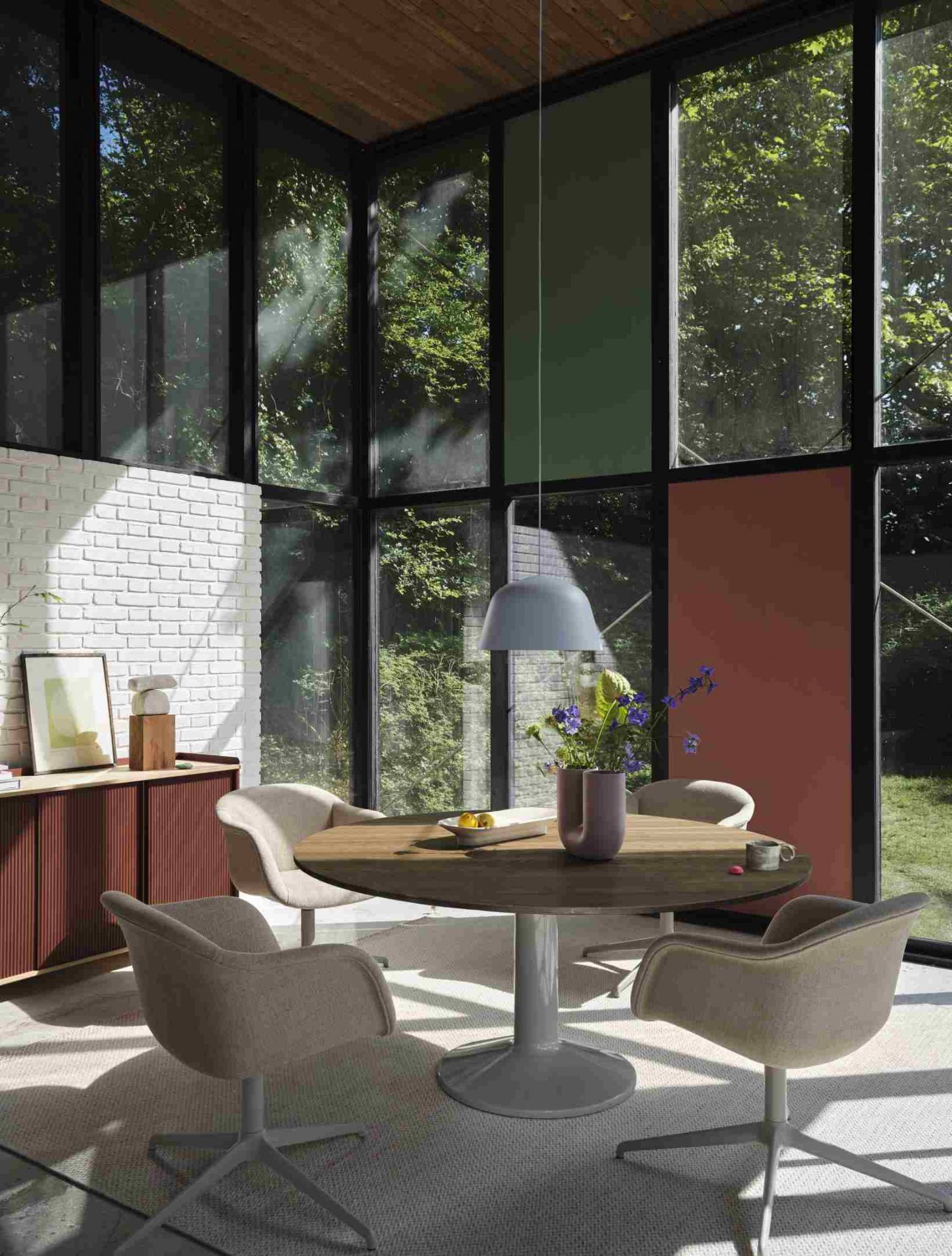 Innenaufnahme mit vier Fiber Armlehnstühlen von Muuto um einen runden Esstisch. Designermöbel für Esszimmer und Wohnbereich.